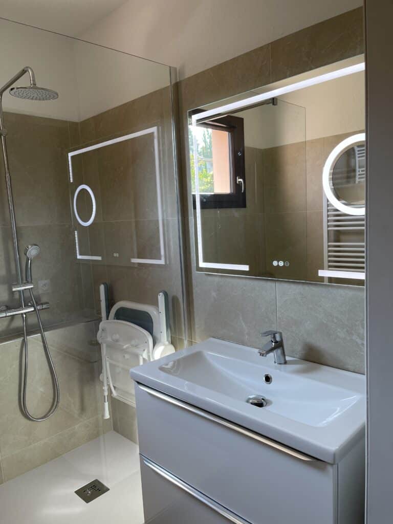 Salle de bain moderne accessible avec douche et siège PMR. Idéale pour projets de rénovation.