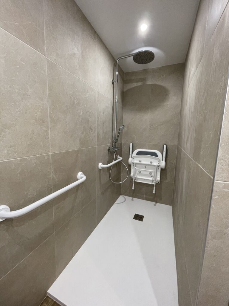Douche spacieuse avec siège pliant et barre. Idéale pour rénovation salle de bains PMR à Grasse.
