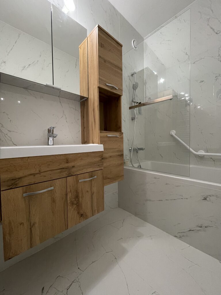 Salle de bain moderne : meuble bois, baignoire, murs et sol marbre.