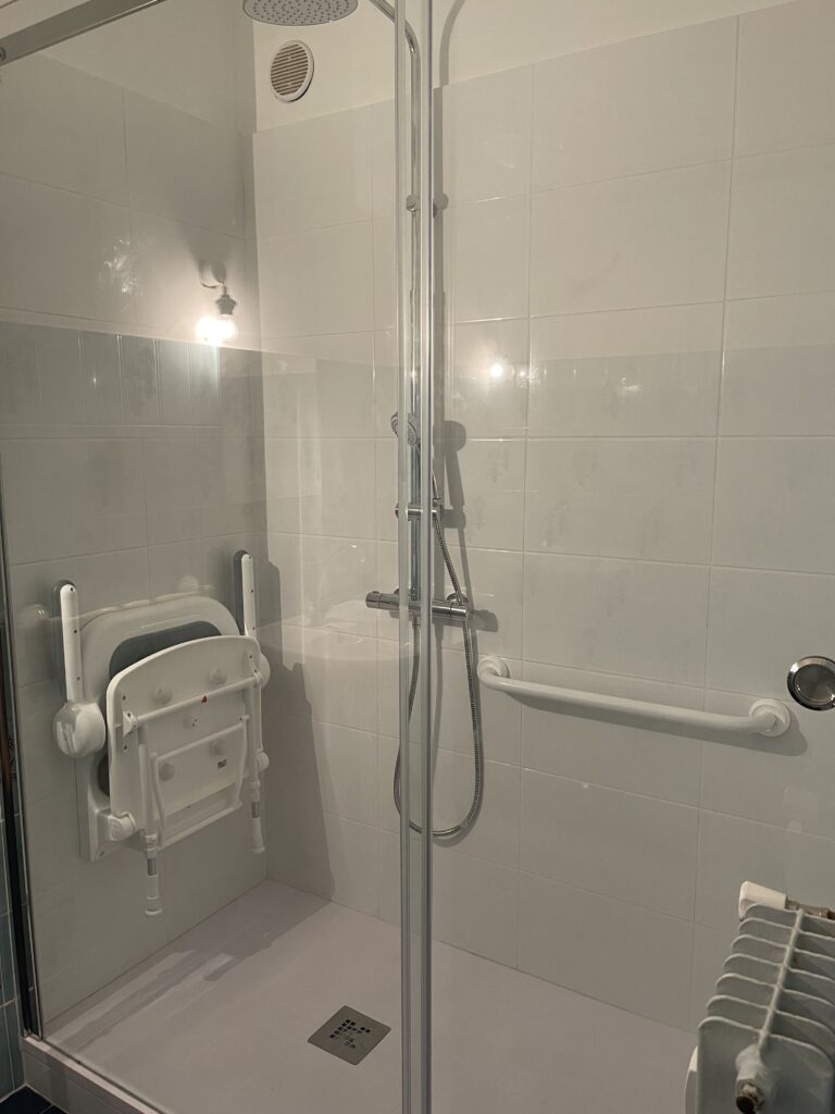Douche carrée : siège pliant, barre, douchette.