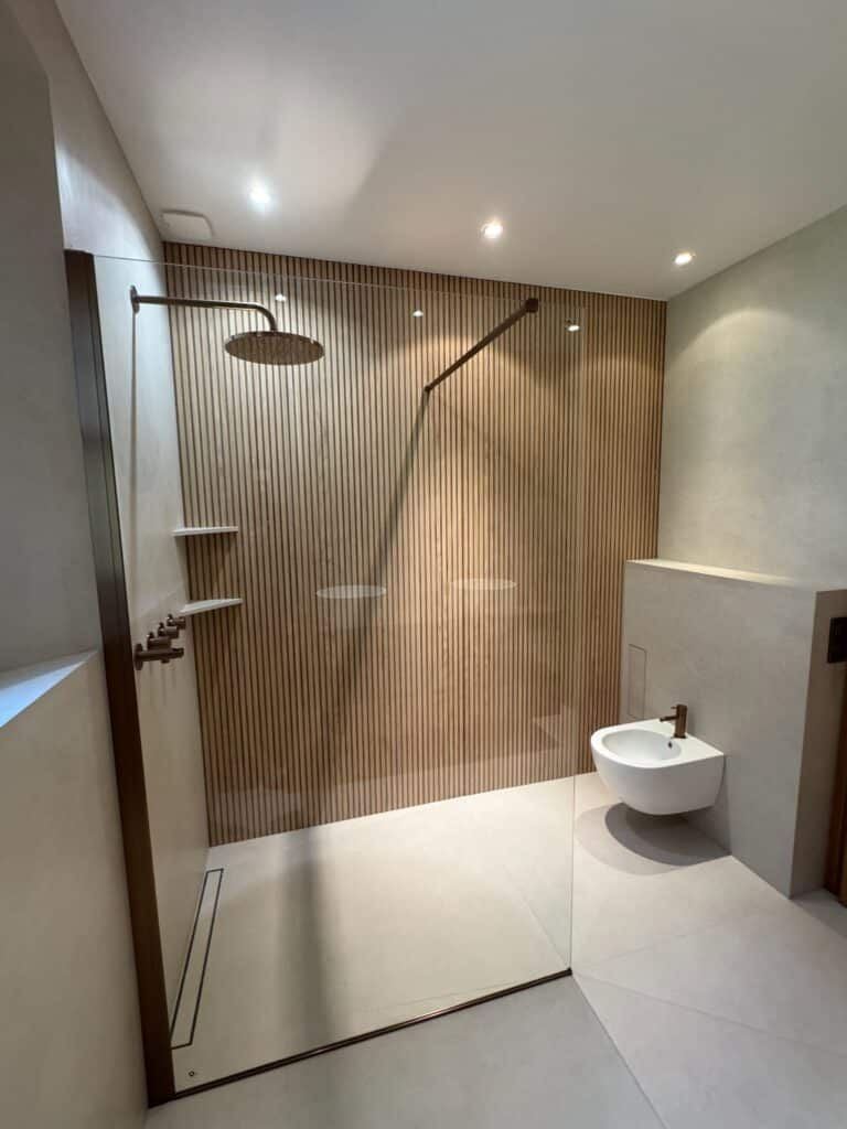 Salle de bains moderne rénovée, douche PMR à l'italienne, design sobre, bois et WC suspendu.
