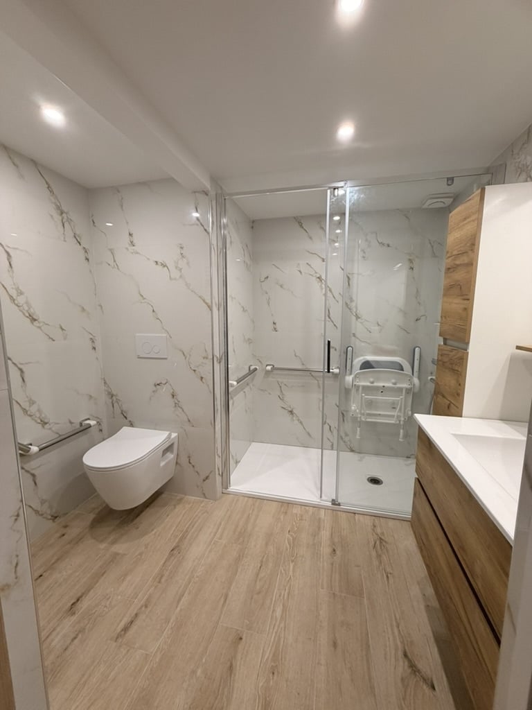 Salle de bain moderne adaptée aux personnes à mobilité réduite, douche accessible, barres d'appui, finitions en bois et marbre à Grasse.