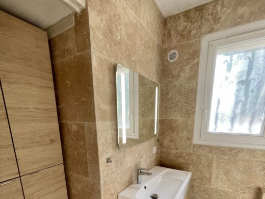 Salle de bain moderne à Grasse avec carrelage brun et vasque sur meuble bois.
