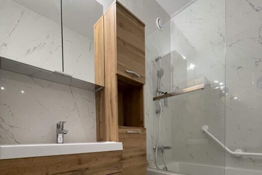 Salle de bain moderne : meuble bois, baignoire, murs et sol marbre.