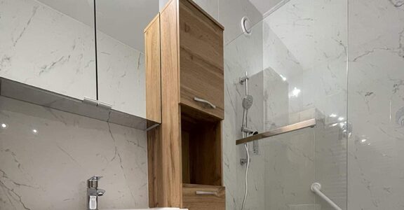 Salle de bain moderne : meuble bois, baignoire, murs et sol marbre.