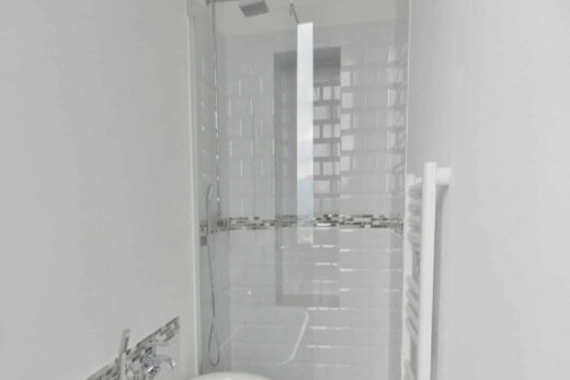 Salle de bain : baignoire autoportante, douche moderne, vanité en bois.